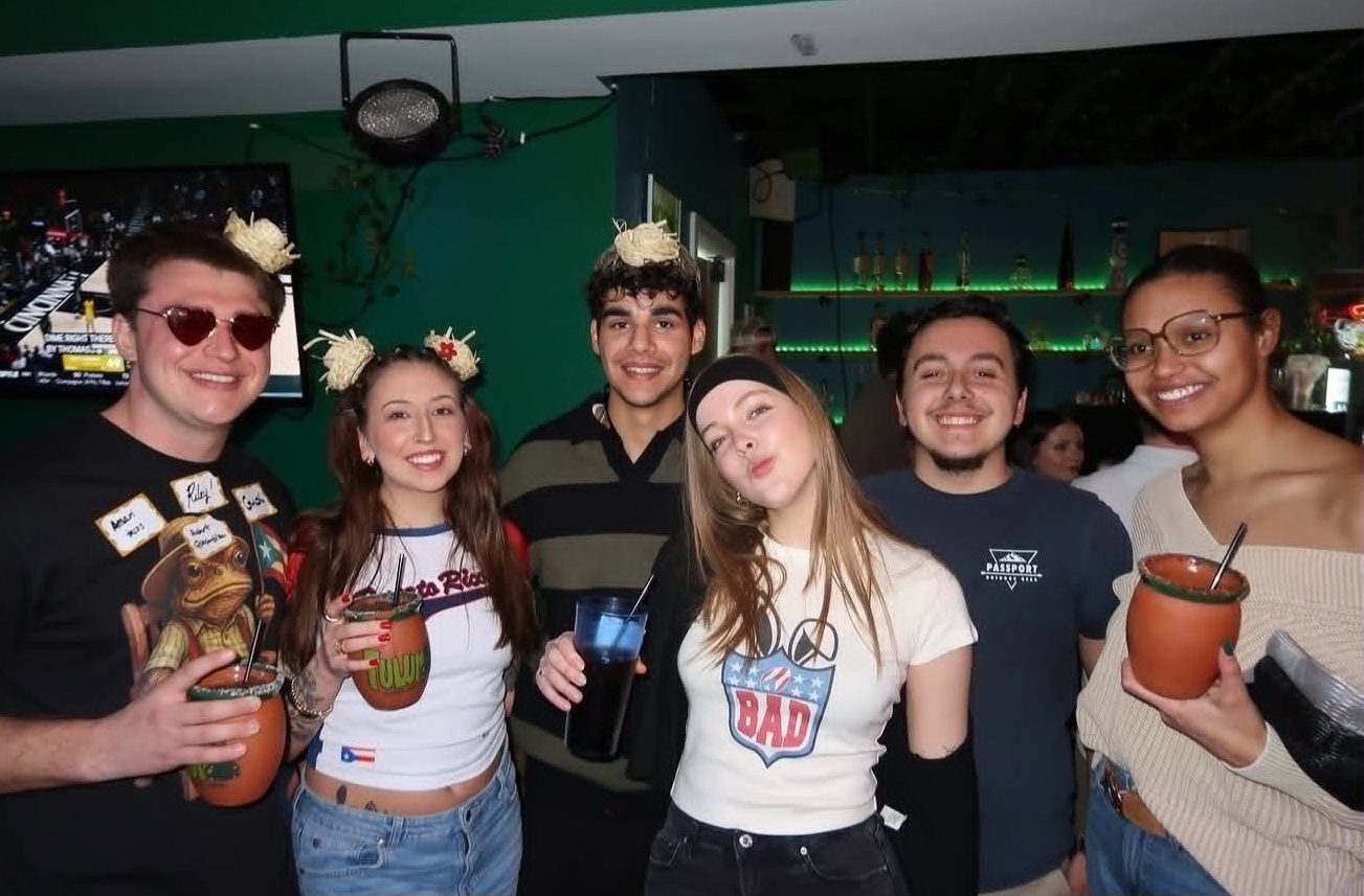 Guests holding hand-painted clay margarita mugs inside Tulum