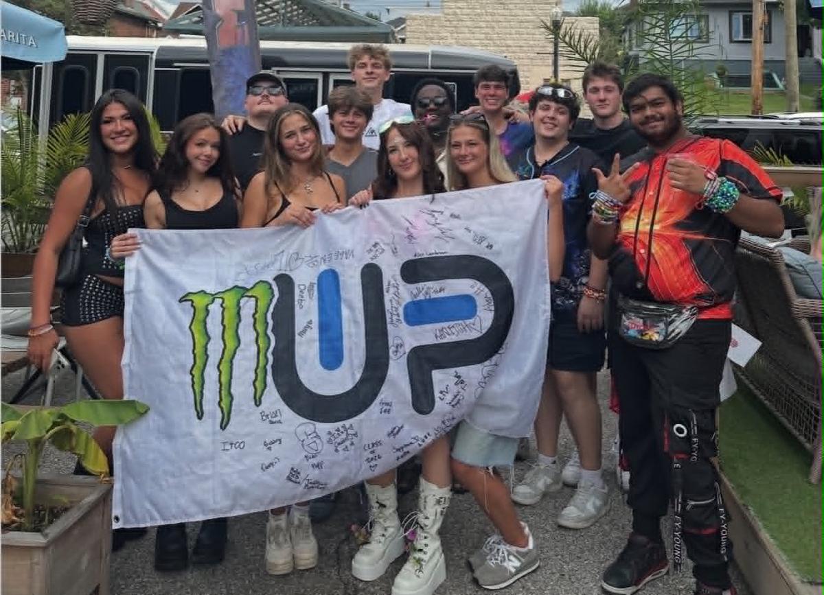 A large group of friends holding a signed flag on Tulum's patio