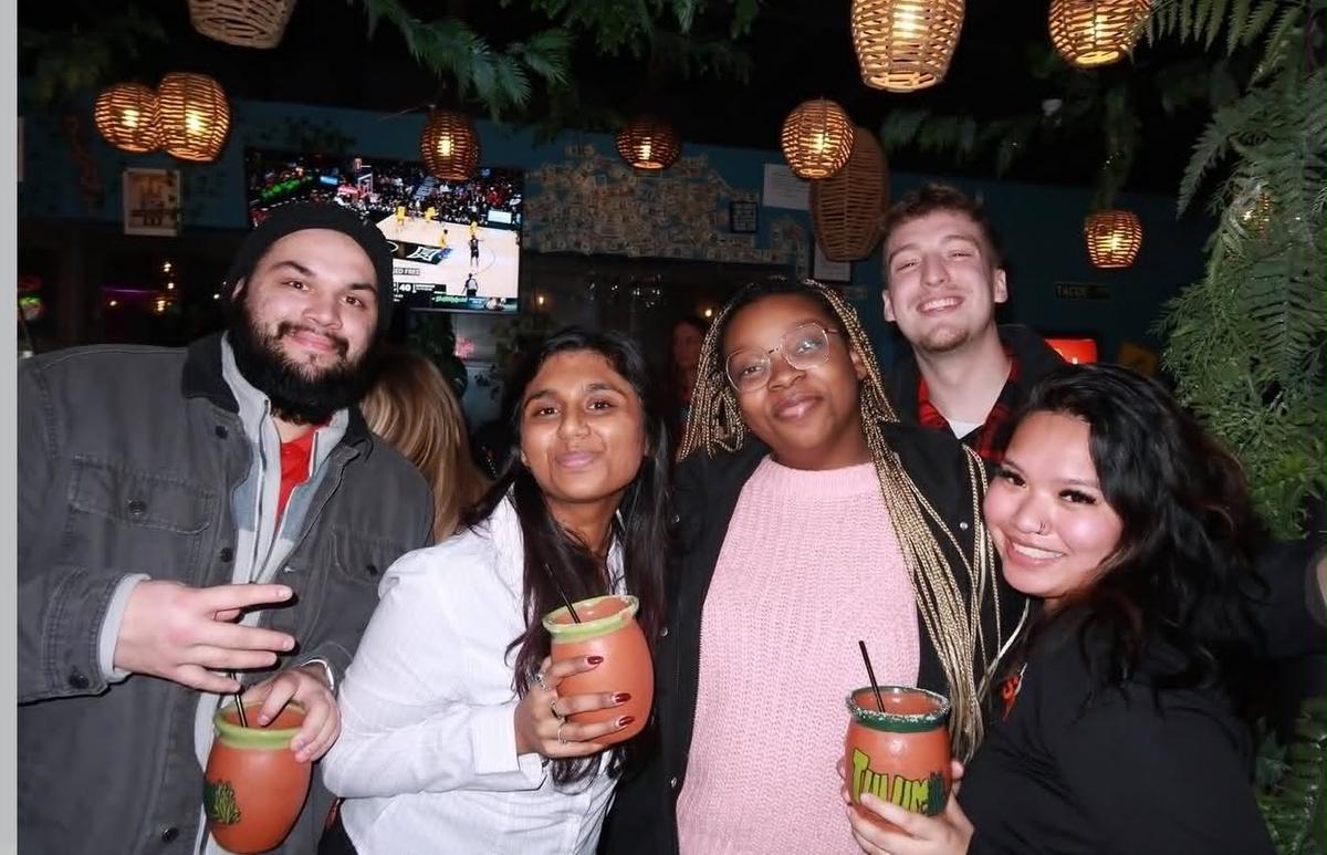 Friends holding clay margarita mugs inside Tulum