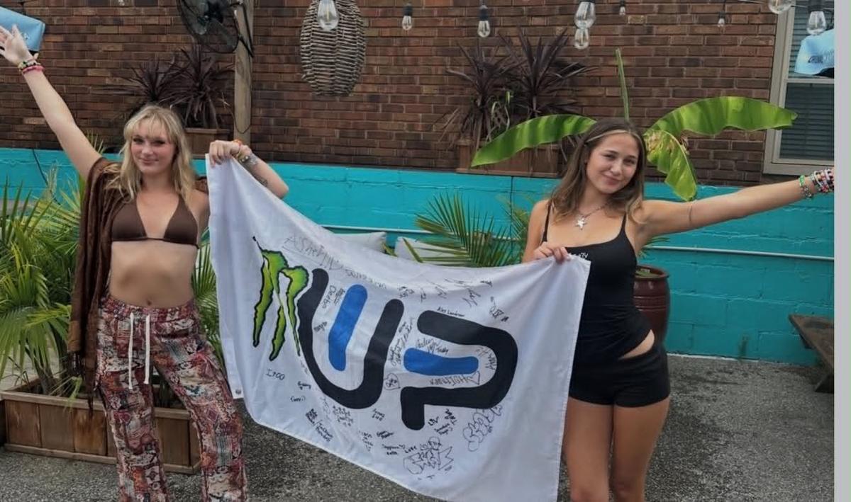Two friends holding a signed flag on the patio