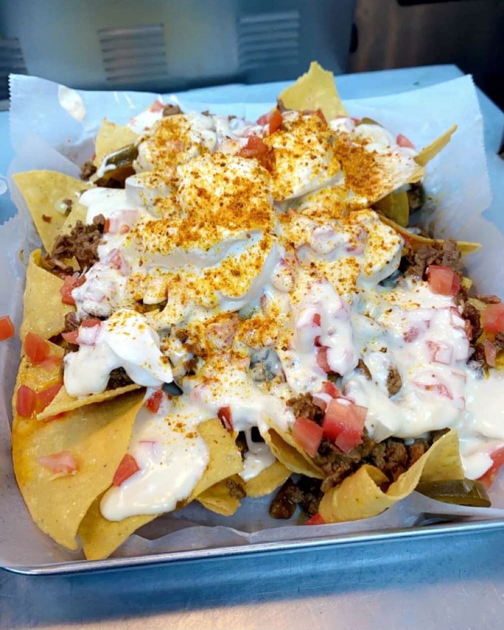 Loaded nachos with seasoned beef, melted cheese, pico de gallo, sour cream and chili powder